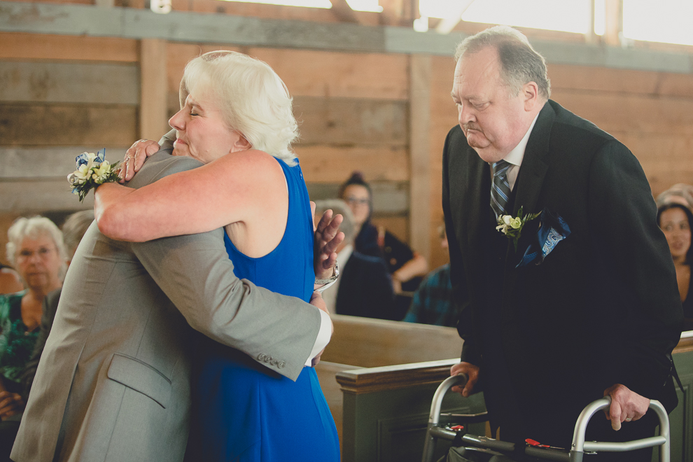 groom and mom hug at wedding ceremony in converted stables at a Hayloft in the Grove wedding in East Aurora, near Buffalo, NY
