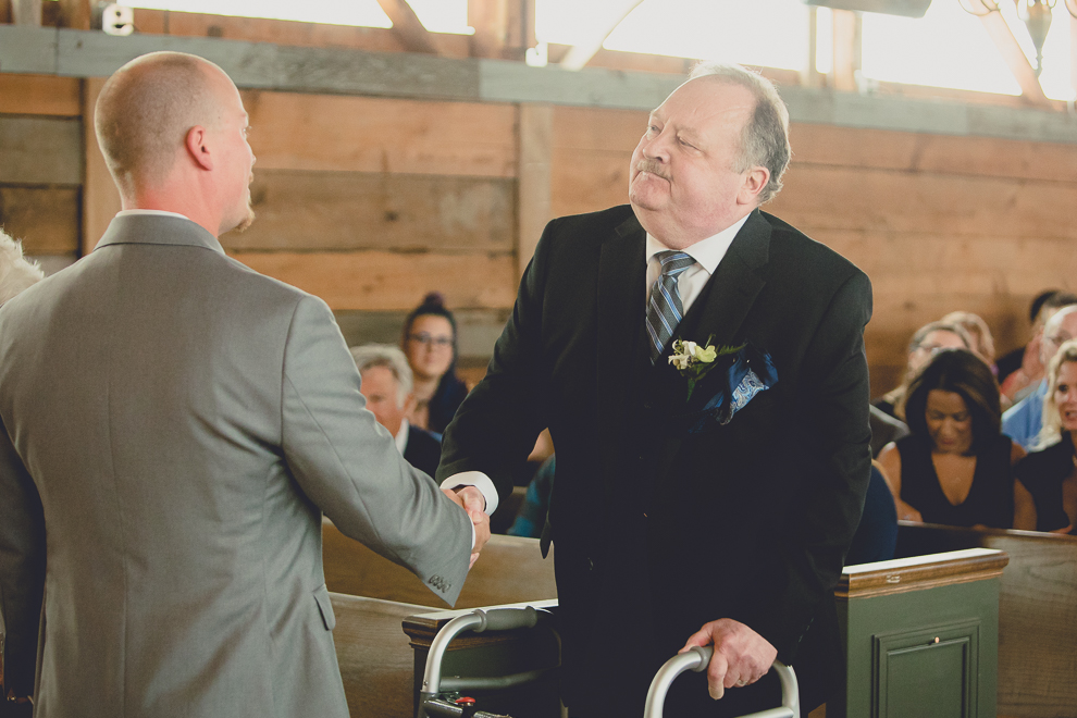 groom and dad shake hands at wedding ceremony in converted stables at a Hayloft in the Grove wedding in East Aurora, near Buffalo, NY