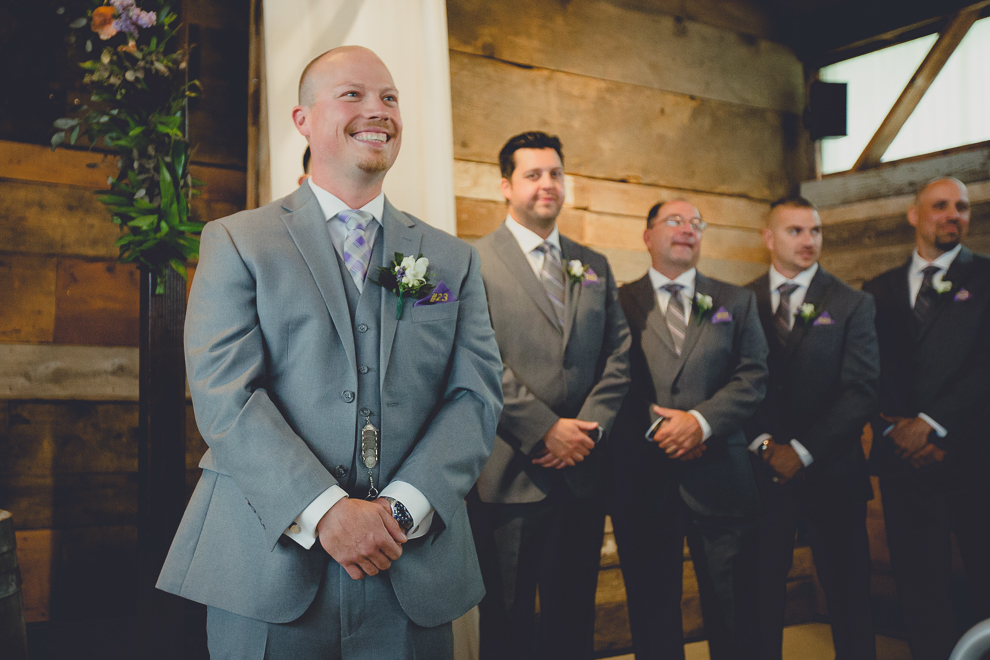 groom smiles as bride and mom walk down aisle at wedding ceremony in converted stables at a Hayloft in the Grove wedding in East Aurora, near Buffalo, NY