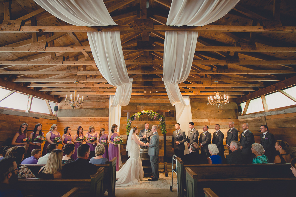 bride and groom smile at each other at wedding ceremony in converted stables at a Hayloft in the Grove in East Aurora, near Buffalo, NY