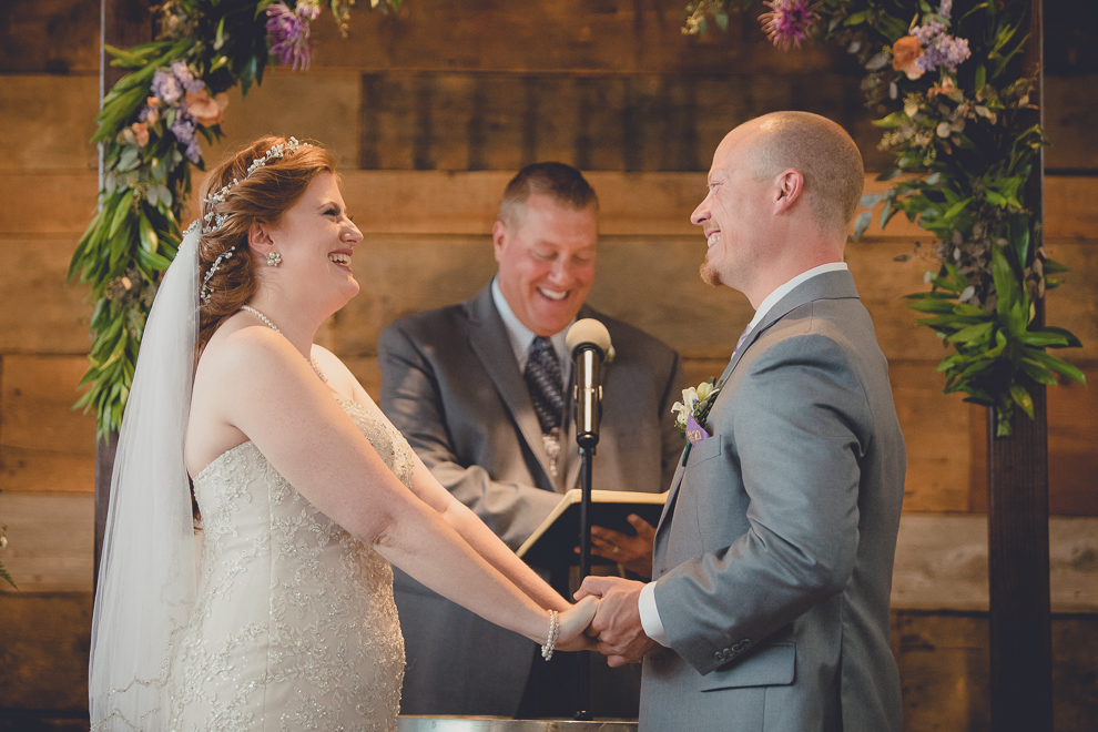 bride and groom smile at each other at wedding ceremony in converted stables at a Hayloft in the Grove in East Aurora, near Buffalo, NY