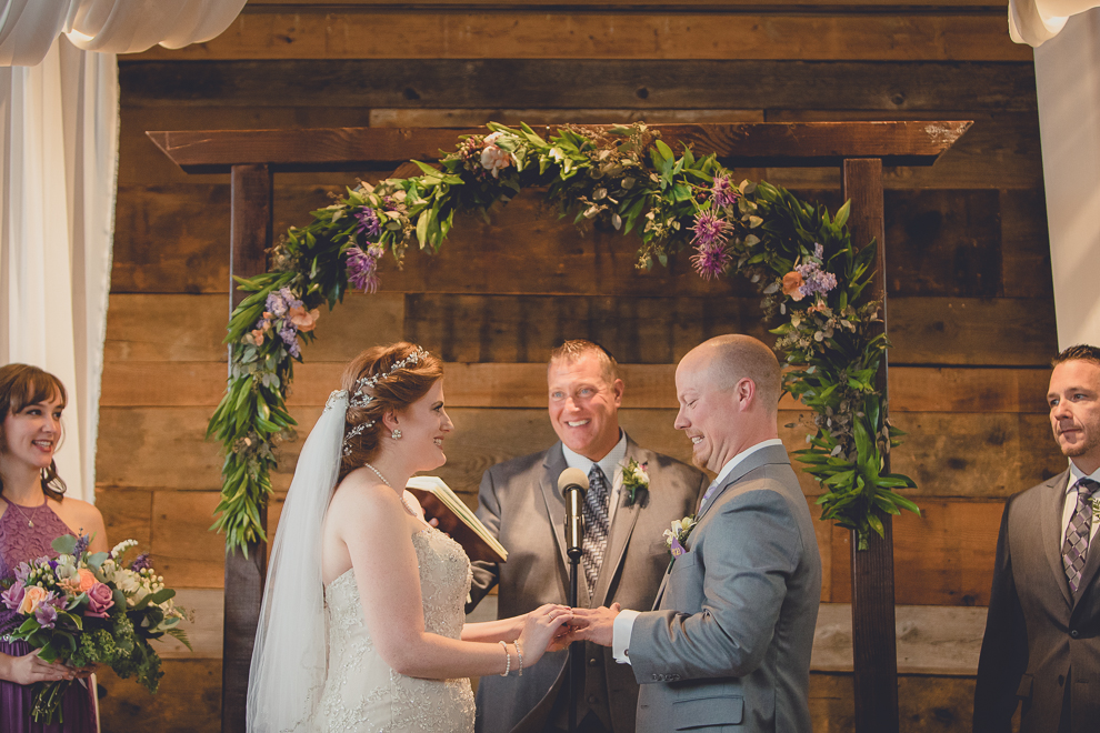 bride and groom exchange rings at wedding ceremony in converted stables at a Hayloft in the Grove in East Aurora, near Buffalo, NY