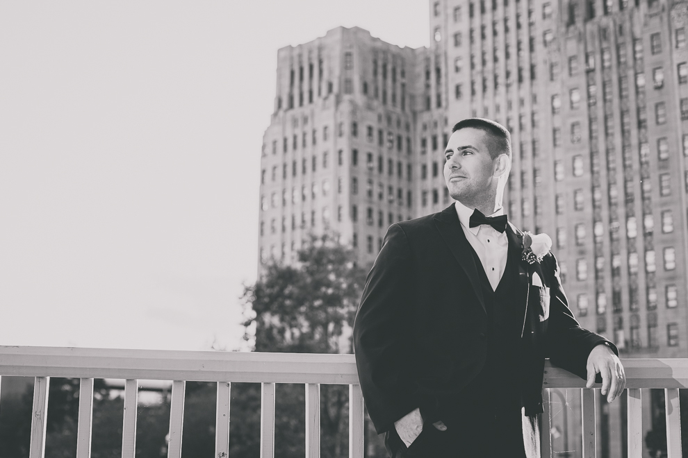 groom poses for portrait with photographer on balcony in Terrace Room at the Statler City wedding reception venue in Buffalo, NY
