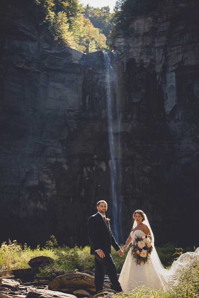 bride and groom stand in front of Taughannock Falls during wedding in Ithaca, NY