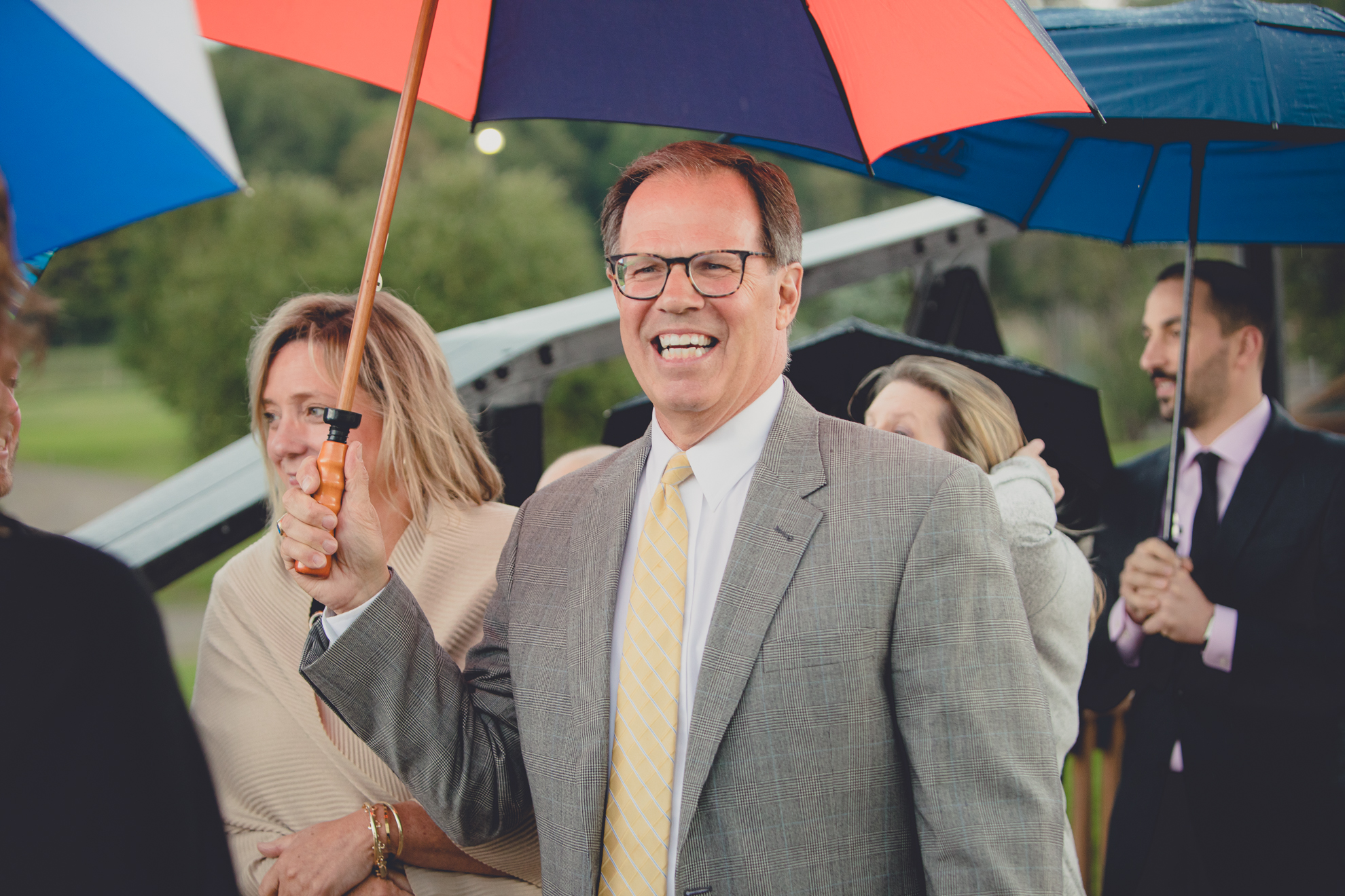 guests hold colorful umbrellas during wedding ceremony at hidden valley animal adventure near Buffalo, NY