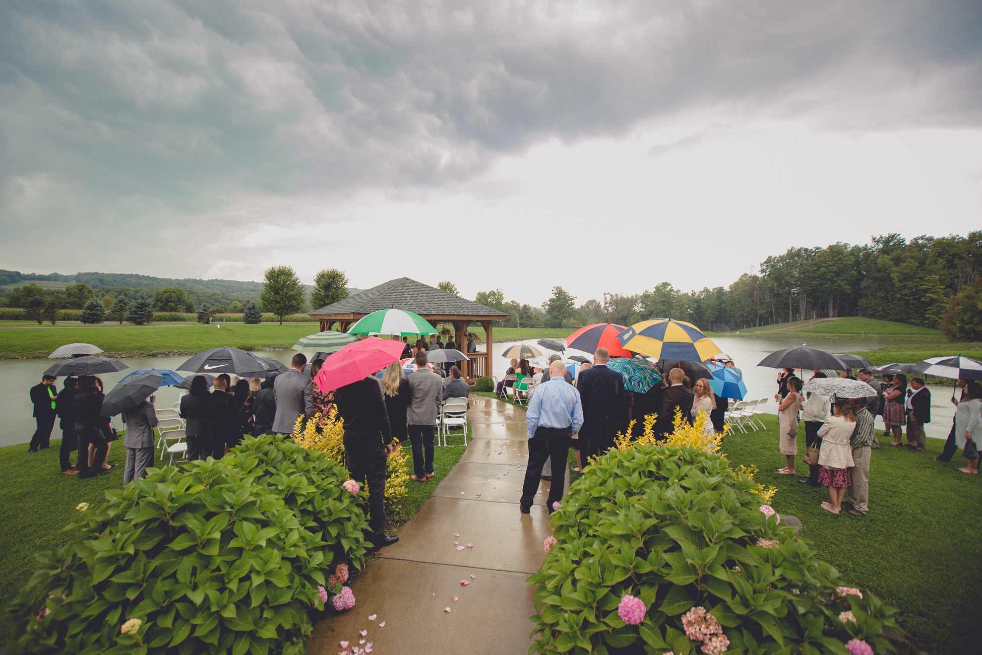 guests hold colorful umbrellas during wedding ceremony at hidden valley animal adventure near Buffalo, NY