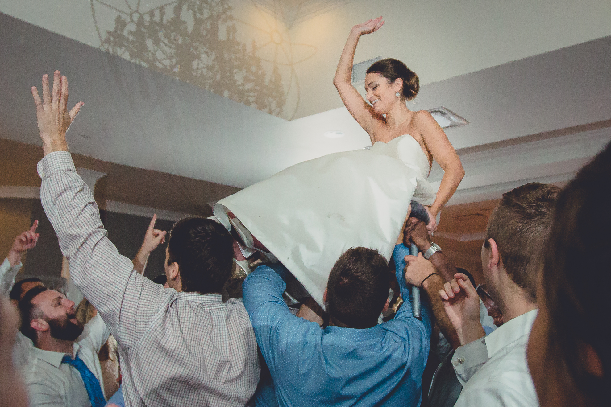 guests lift bride above their heads at wedding reception at Niagara Falls Country Club in Lewiston, NY