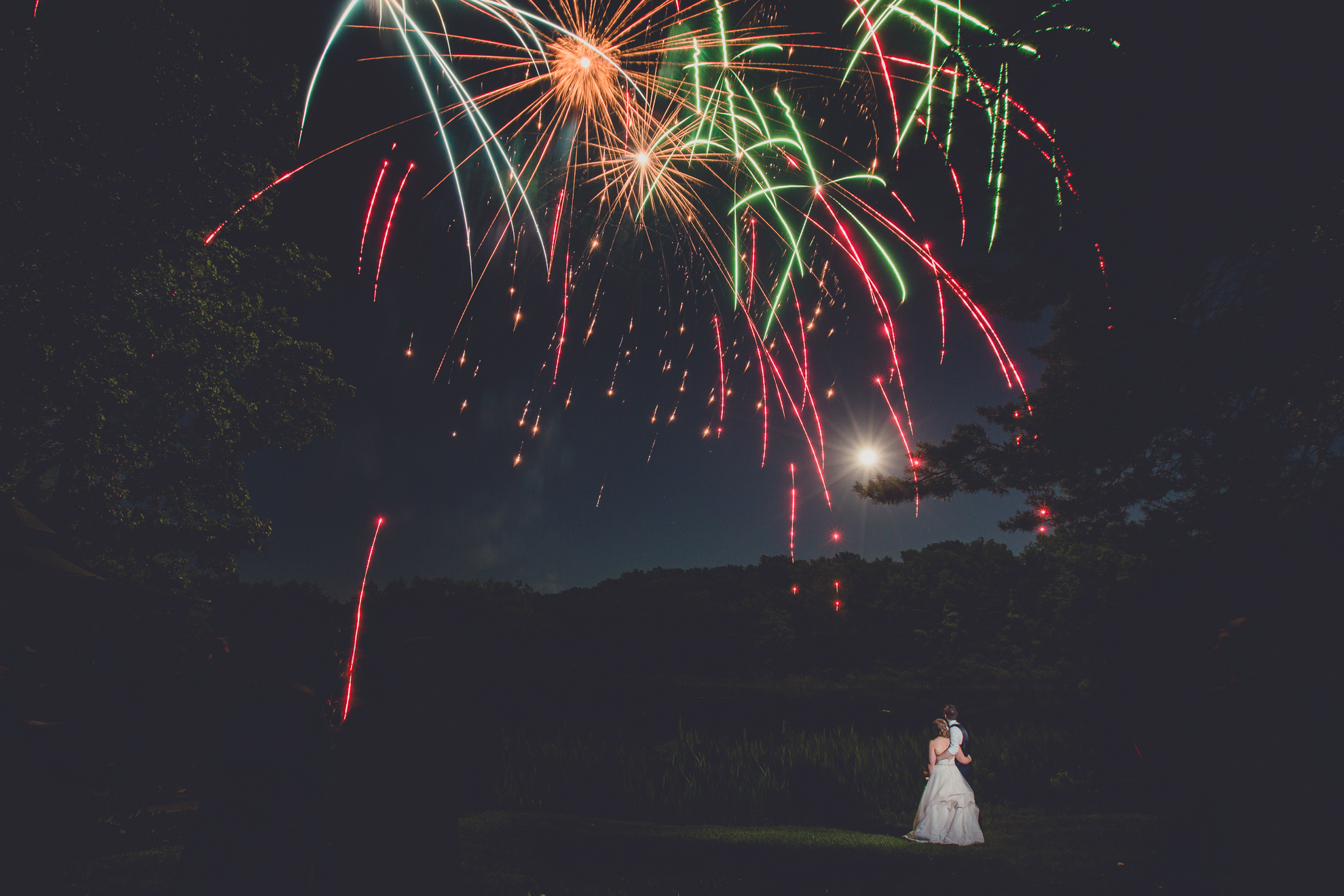 bride and groom watch fireworks in front of full moon during outdoor wedding reception at Spring Lake Winery venue near Buffalo in WNY