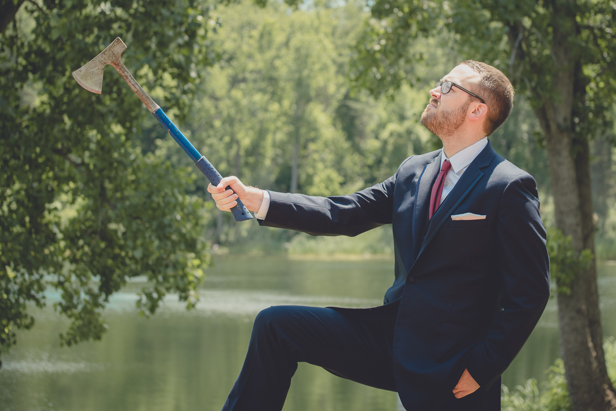 groom poses with axe at Spring Lake Winery in Niagara County before WNY wedding