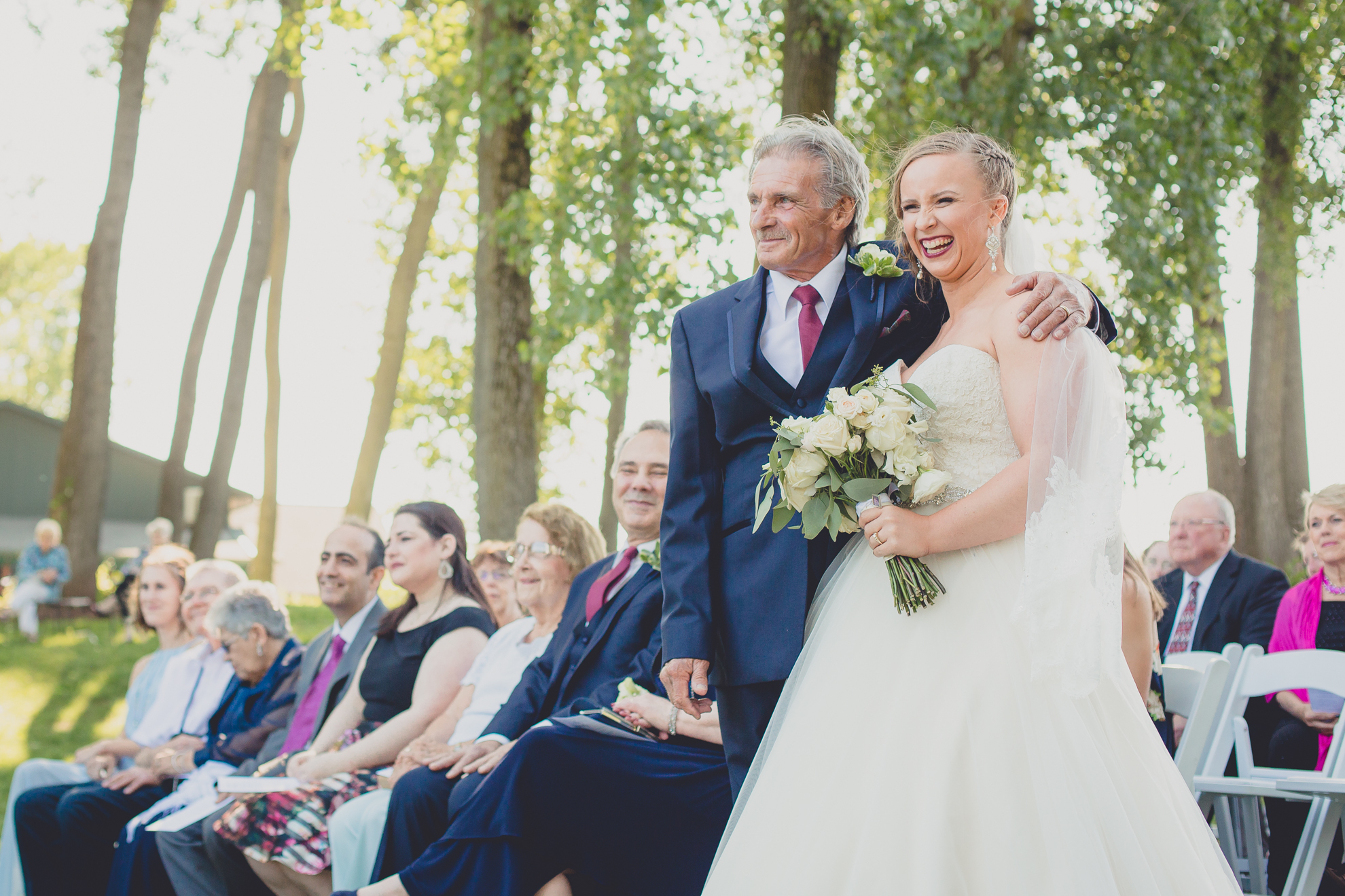 father and bride embrace and laugh after processional at Spring Lake Winery in Niagara County before wedding near Buffalo, NY