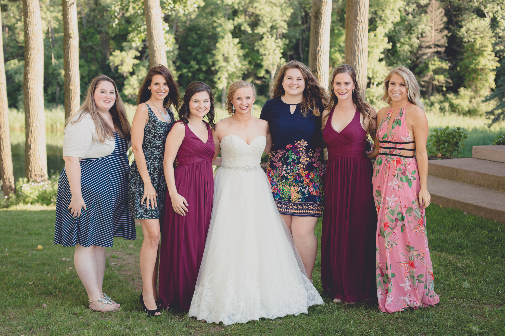 bride poses for portrait with cousins during outdoor wedding reception at Spring Lake Winery near Buffalo in WNY