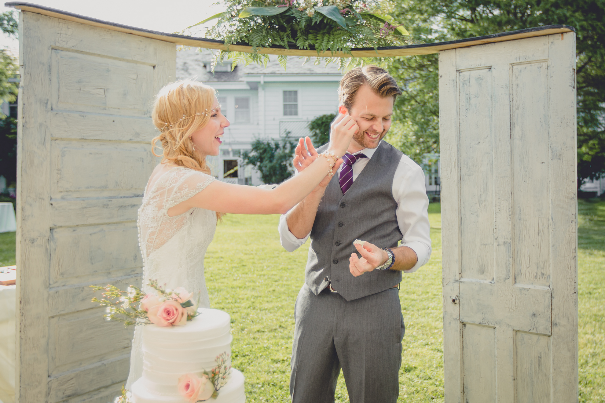 bride and groom feed each other cake under tent at reception at small wedding at Knox Farm near Buffalo, NY