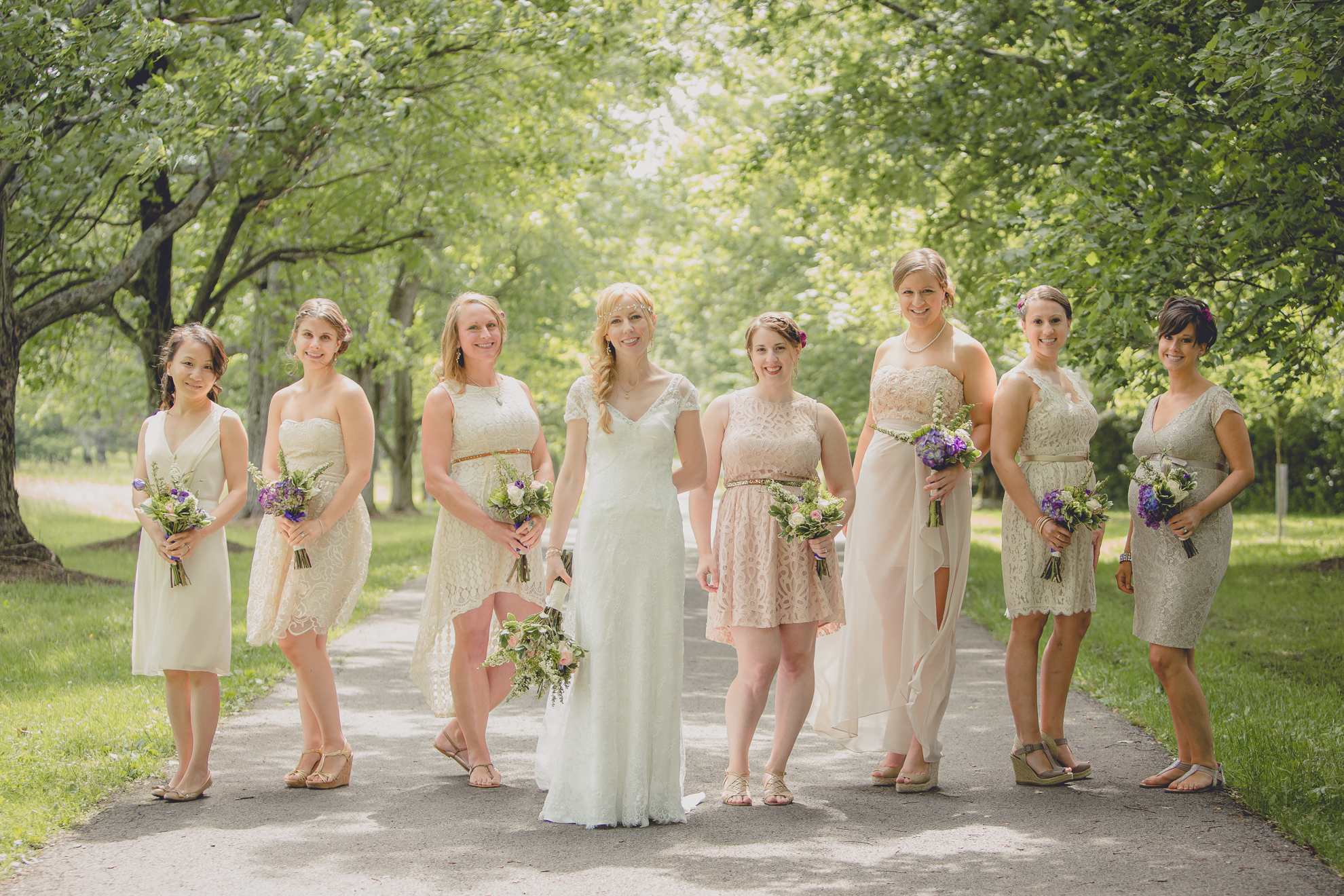 bridesmaids stand for portraits on tree lined road at small wedding at Knox Farm near Buffalo, NY