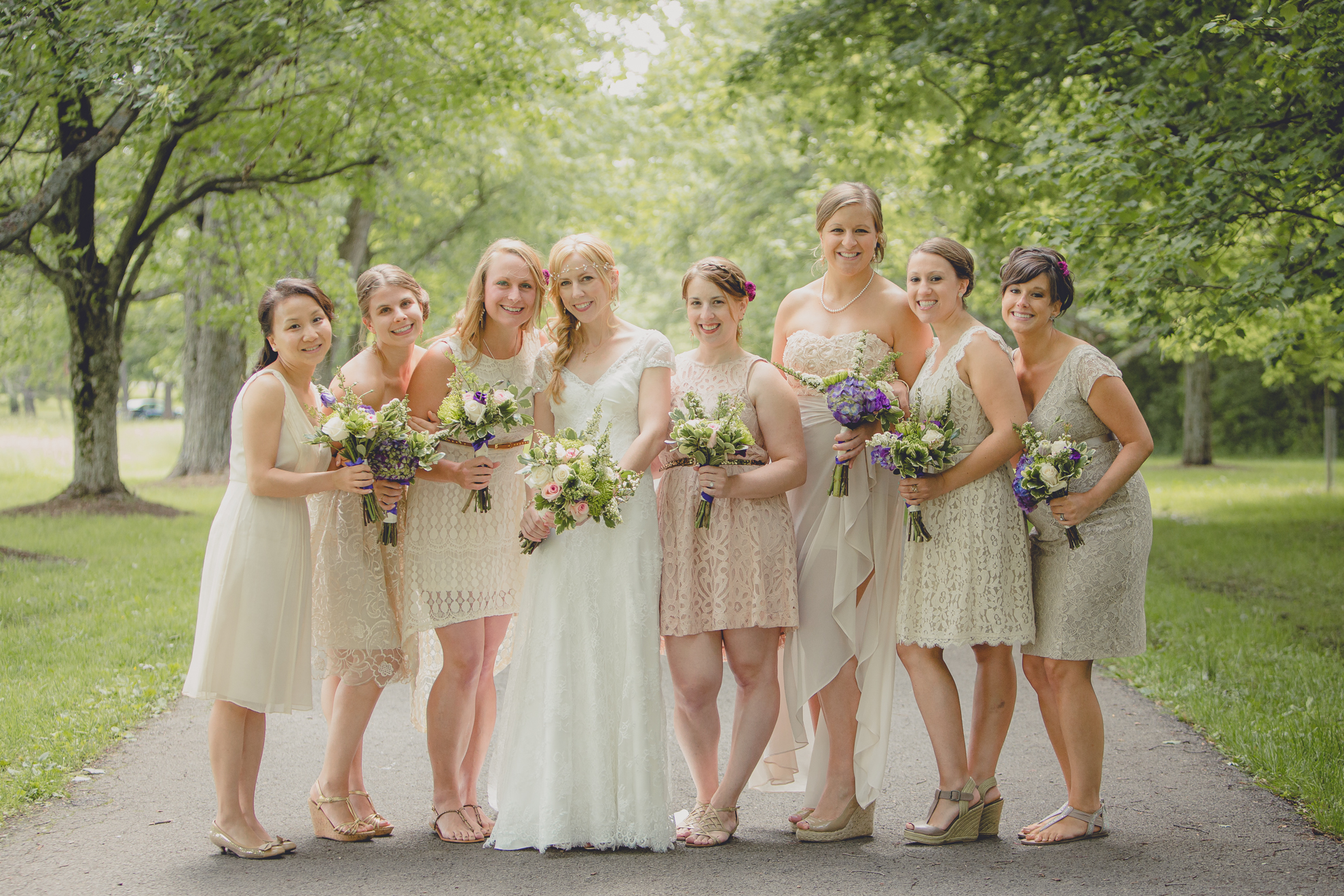 bridesmaids stand for portraits on tree lined road at small wedding at Knox Farm near Buffalo, NY