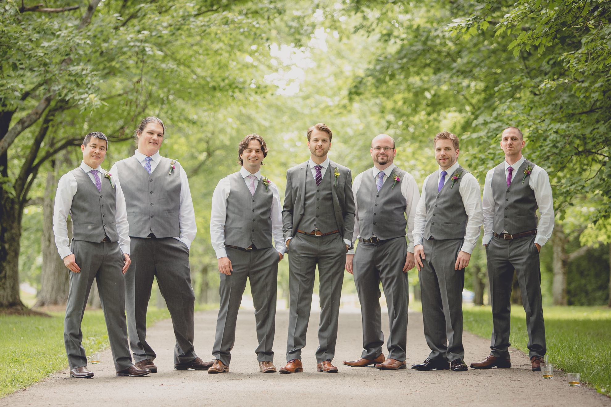 groomsmen pose for portraits on tree lined road at small wedding at Knox Farm near Buffalo, NY