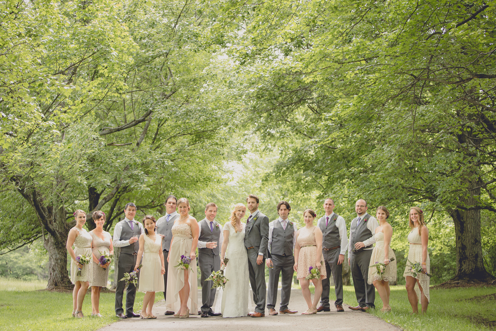 wedding party poses for portraits on tree lined road at small wedding at Knox Farm near Buffalo, NY