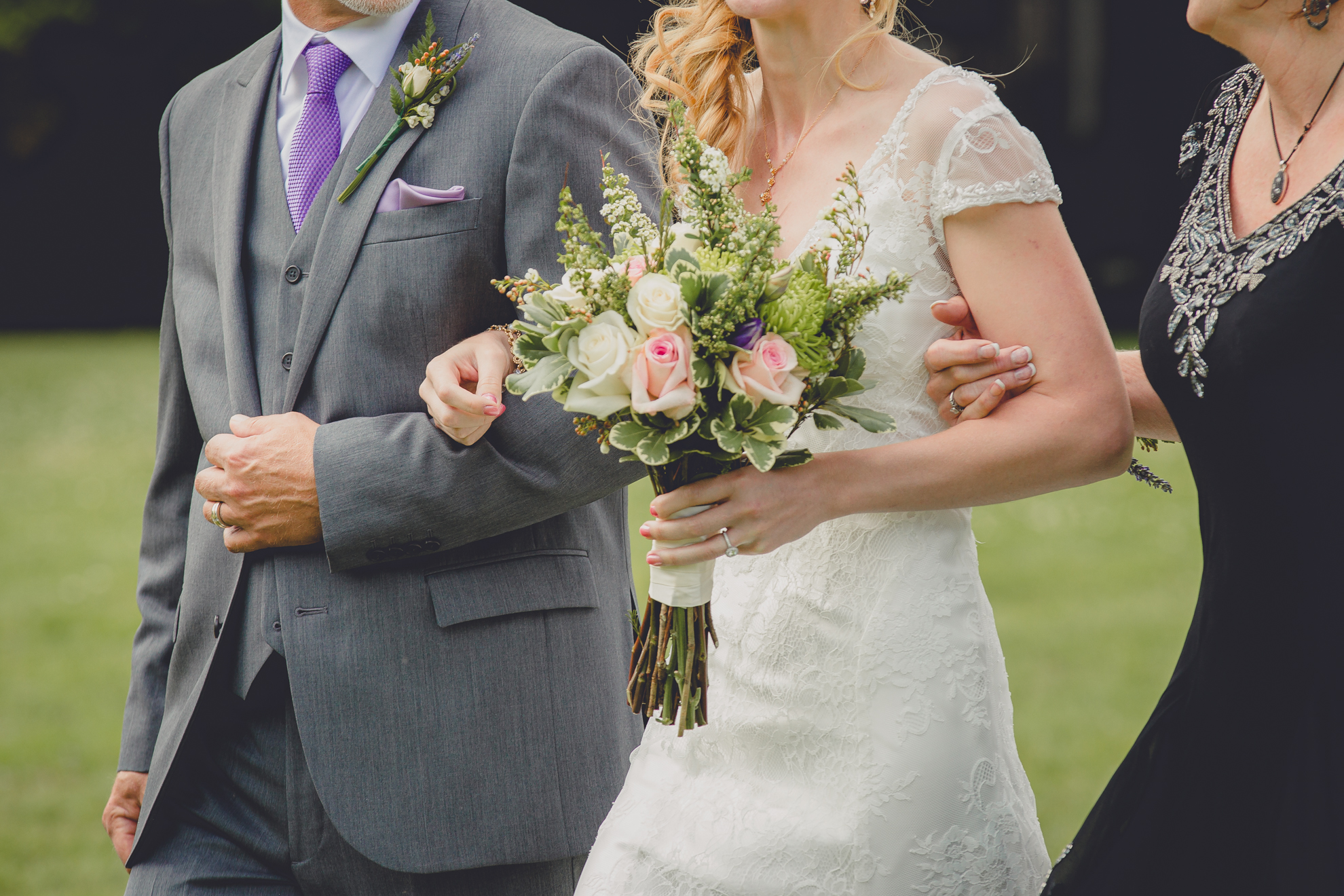 mother and father of bride escort bride through grass before ceremony at small wedding at Knox Farm near Buffalo, NY