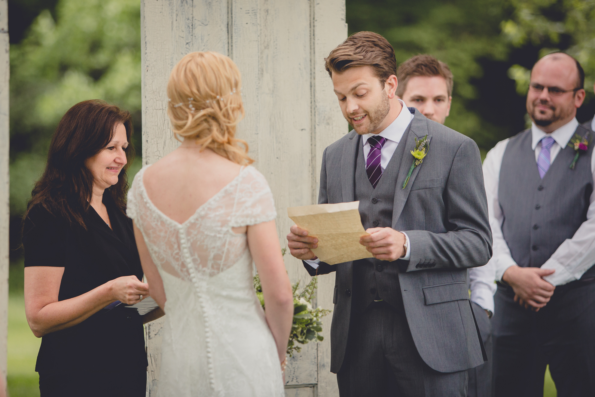 groom reads vows to bride during ceremony at small wedding at Knox Farm near Buffalo, NY