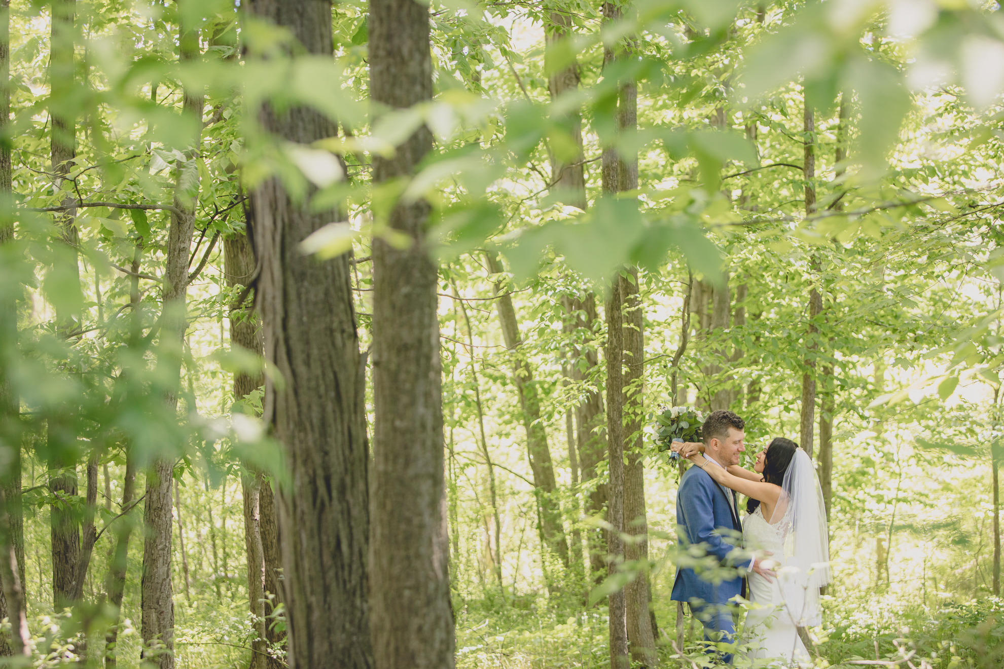 bride and groom embrace in woods after small backyard micro wedding in Buffalo, NY