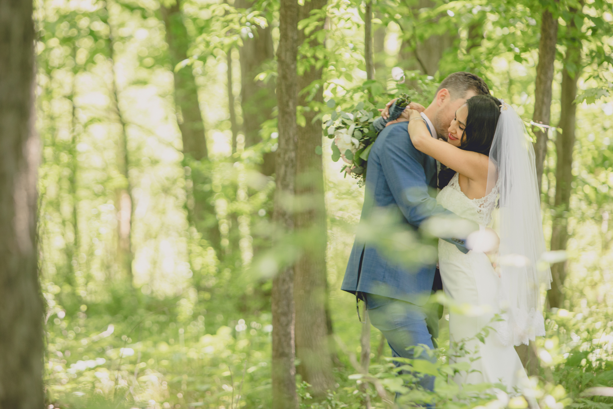 bride and groom hug in woods after small backyard micro wedding in Buffalo, NY