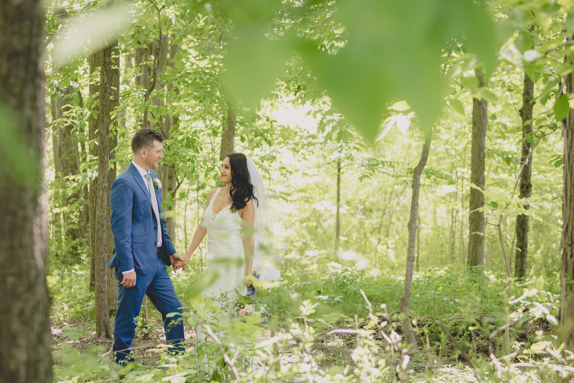 bride and groom hold hands in woods after small backyard micro wedding in Buffalo, NY