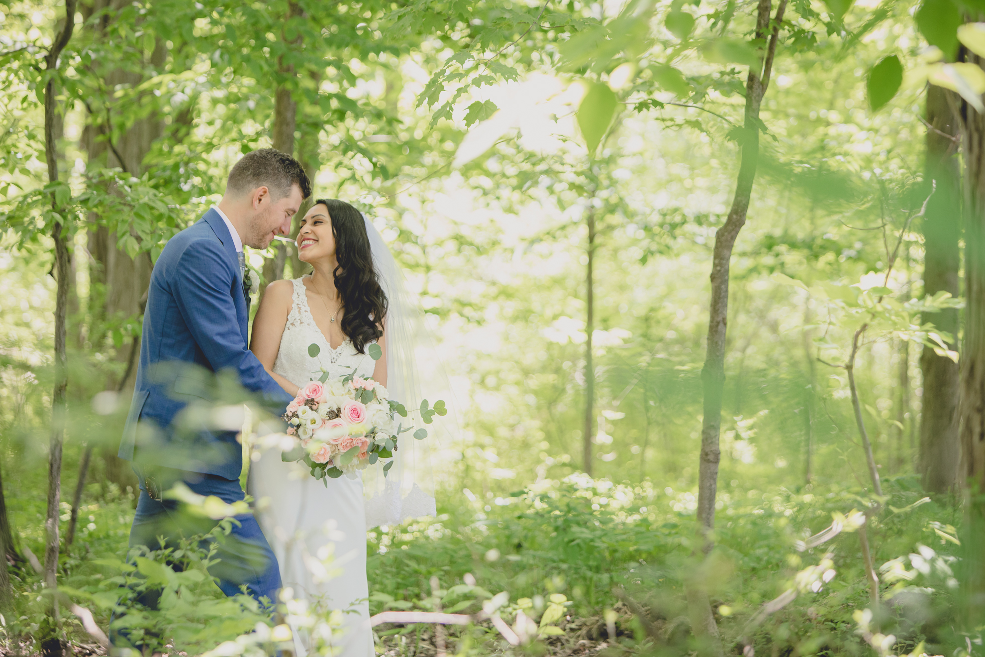 bride and groom smile at each other in woods after small backyard micro wedding in Buffalo, NY