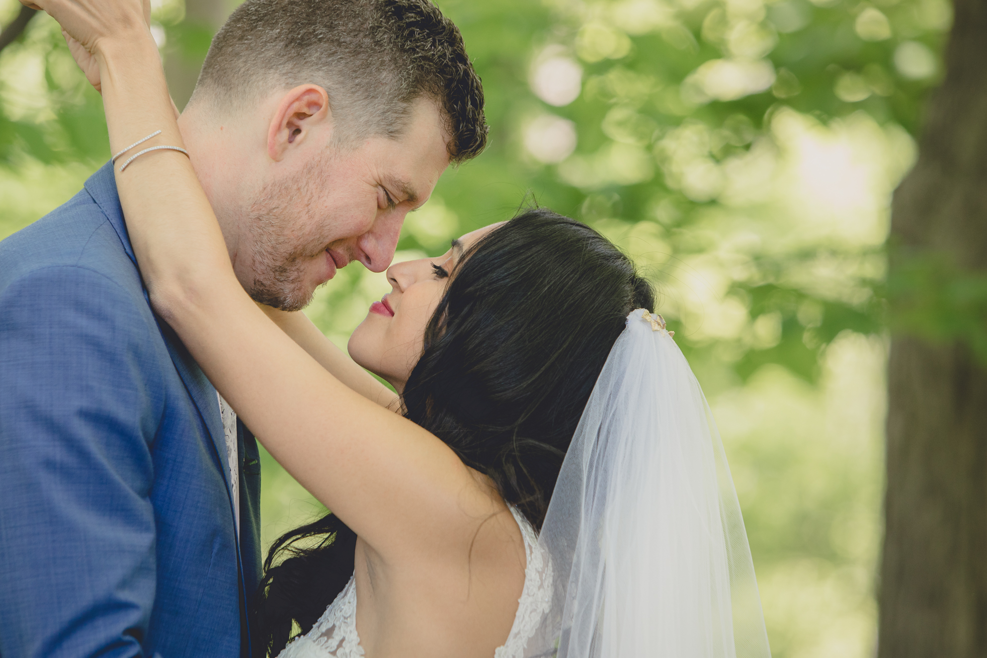 bride and groom touch noses in forest after small backyard micro wedding in Buffalo, NY