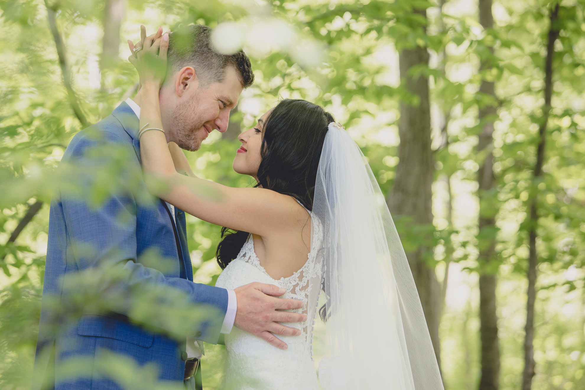 bride and groom smile at each other in forest after small backyard micro wedding in Buffalo, NY