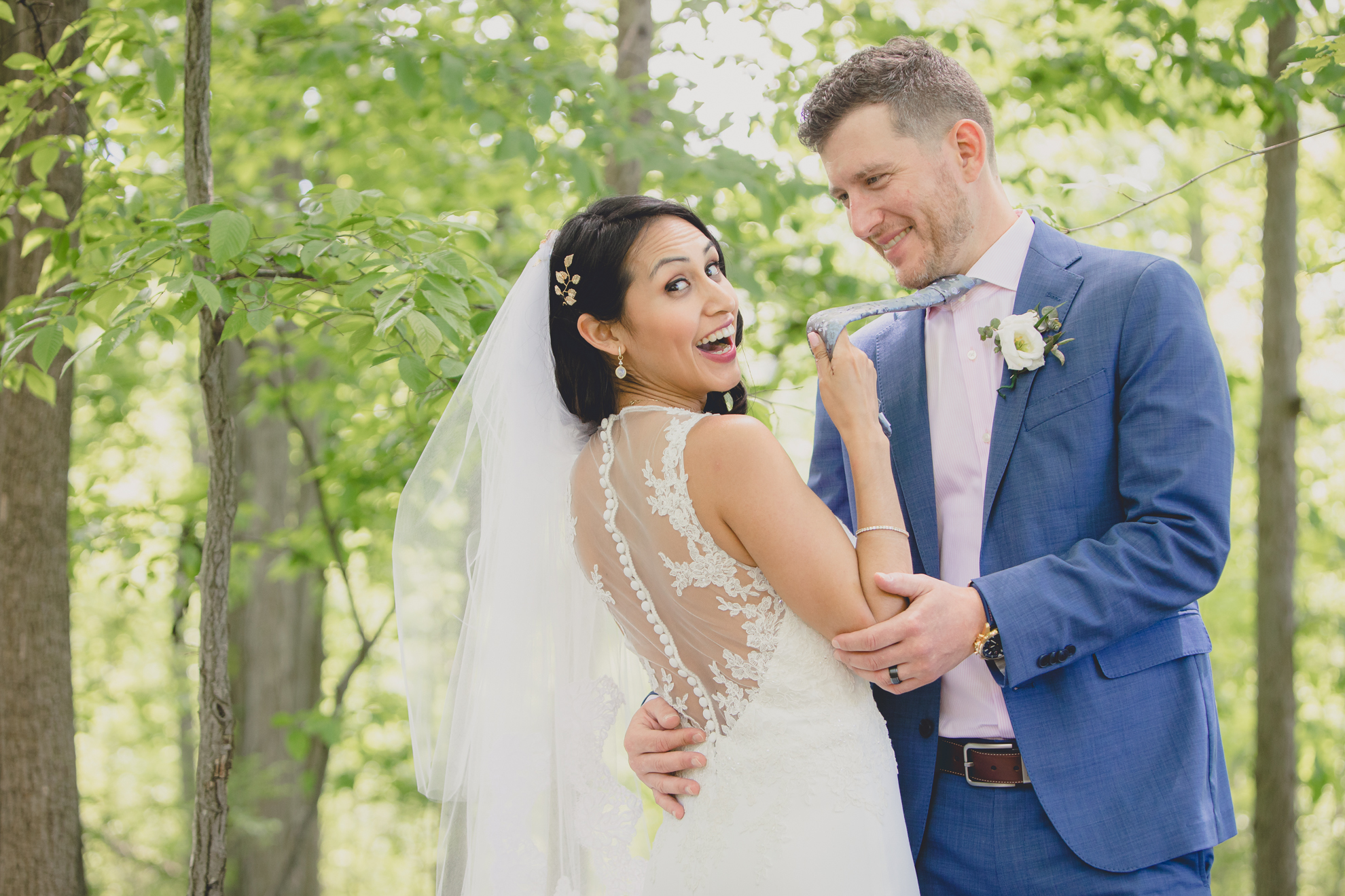 bride grabs groom's tie and laughs in forest after small backyard micro wedding in Buffalo, NY