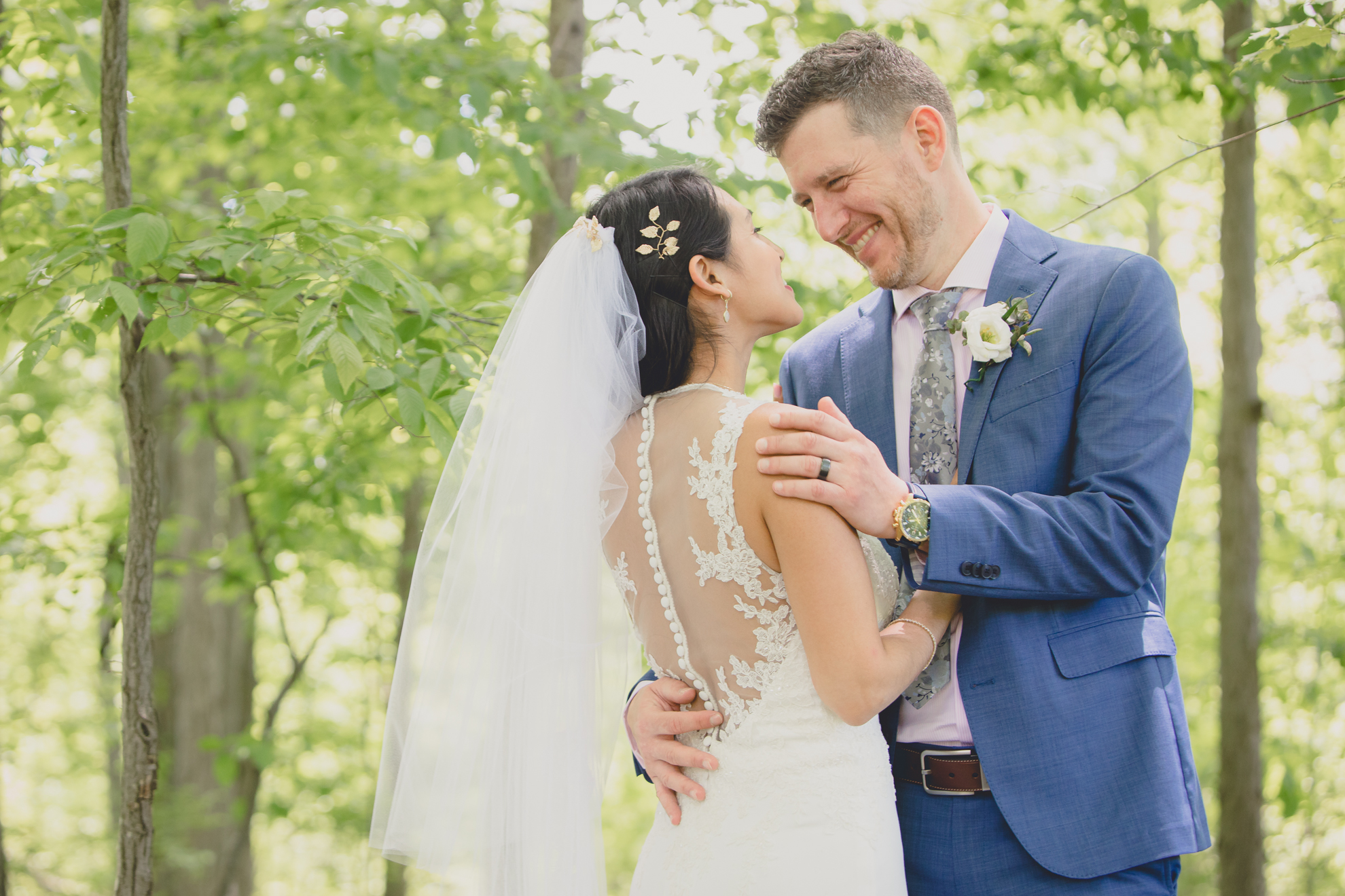 groom smiles at bride in forest after small backyard micro wedding in Buffalo, NY
