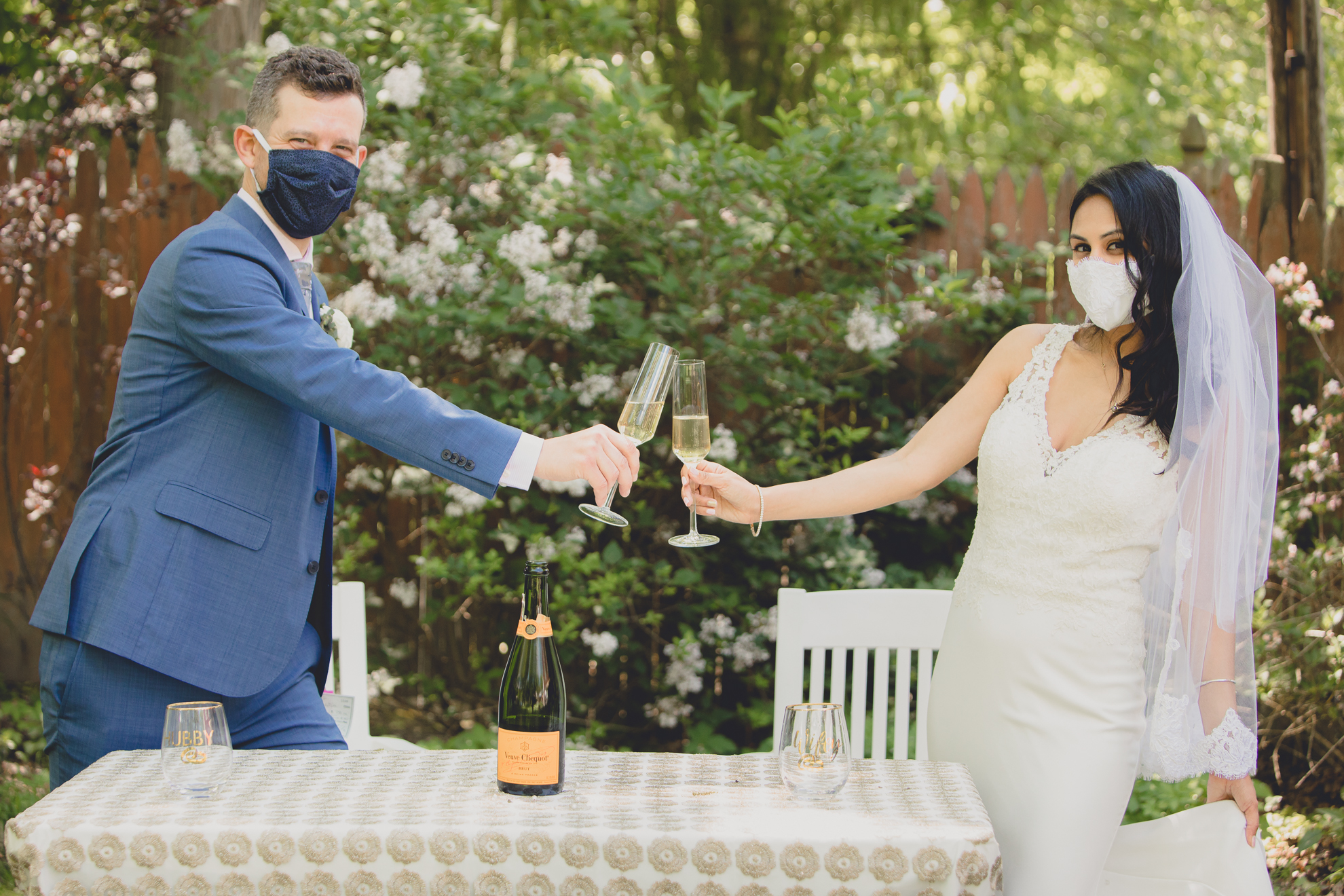 bride and groom cheers while wearing covid-19 masks during small backyard intimate wedding reception in Buffalo, NY