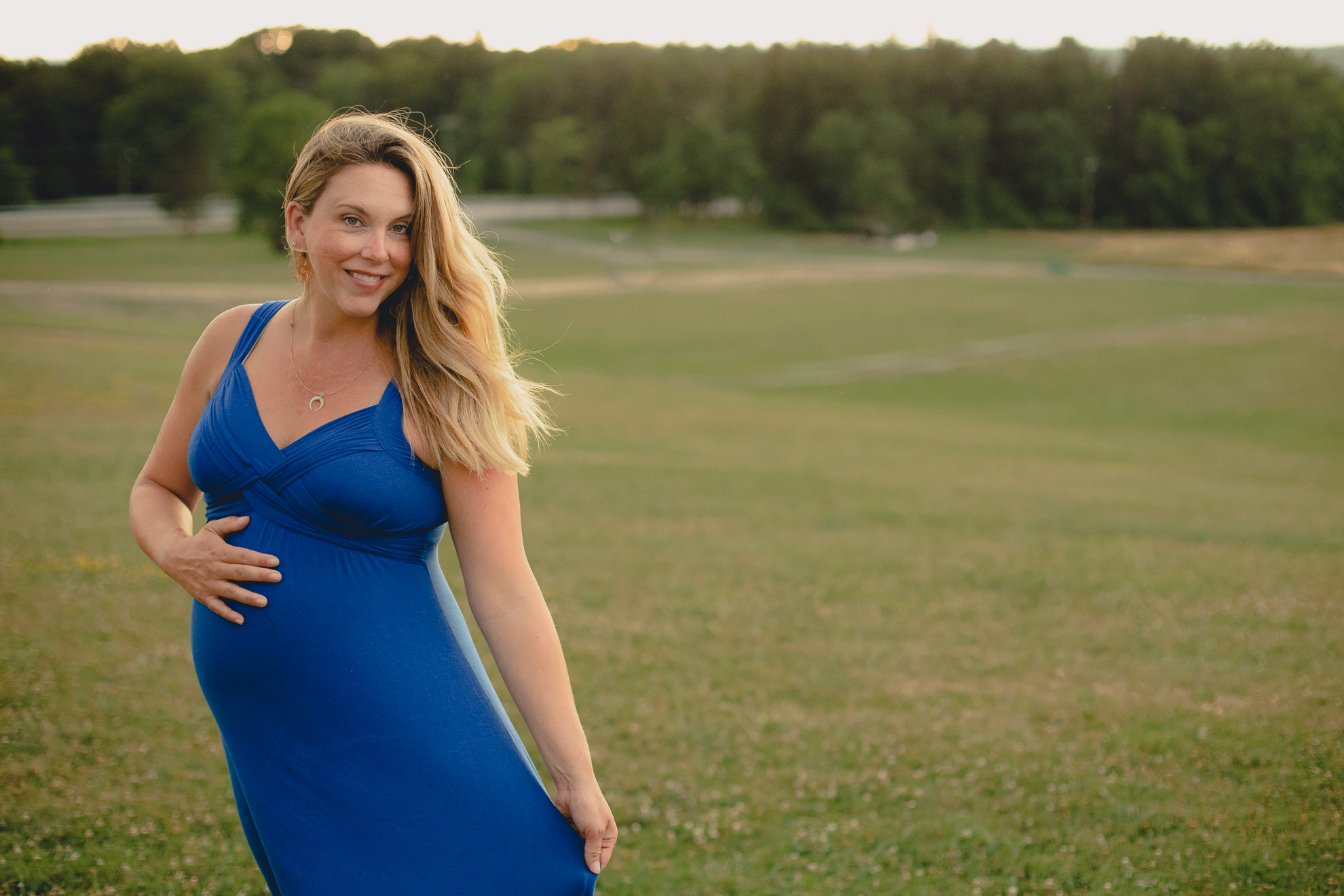 maternity portrait of expecting mother smiling for photographer in grasst field at Chestnut Ridge Park near Buffalo, NY