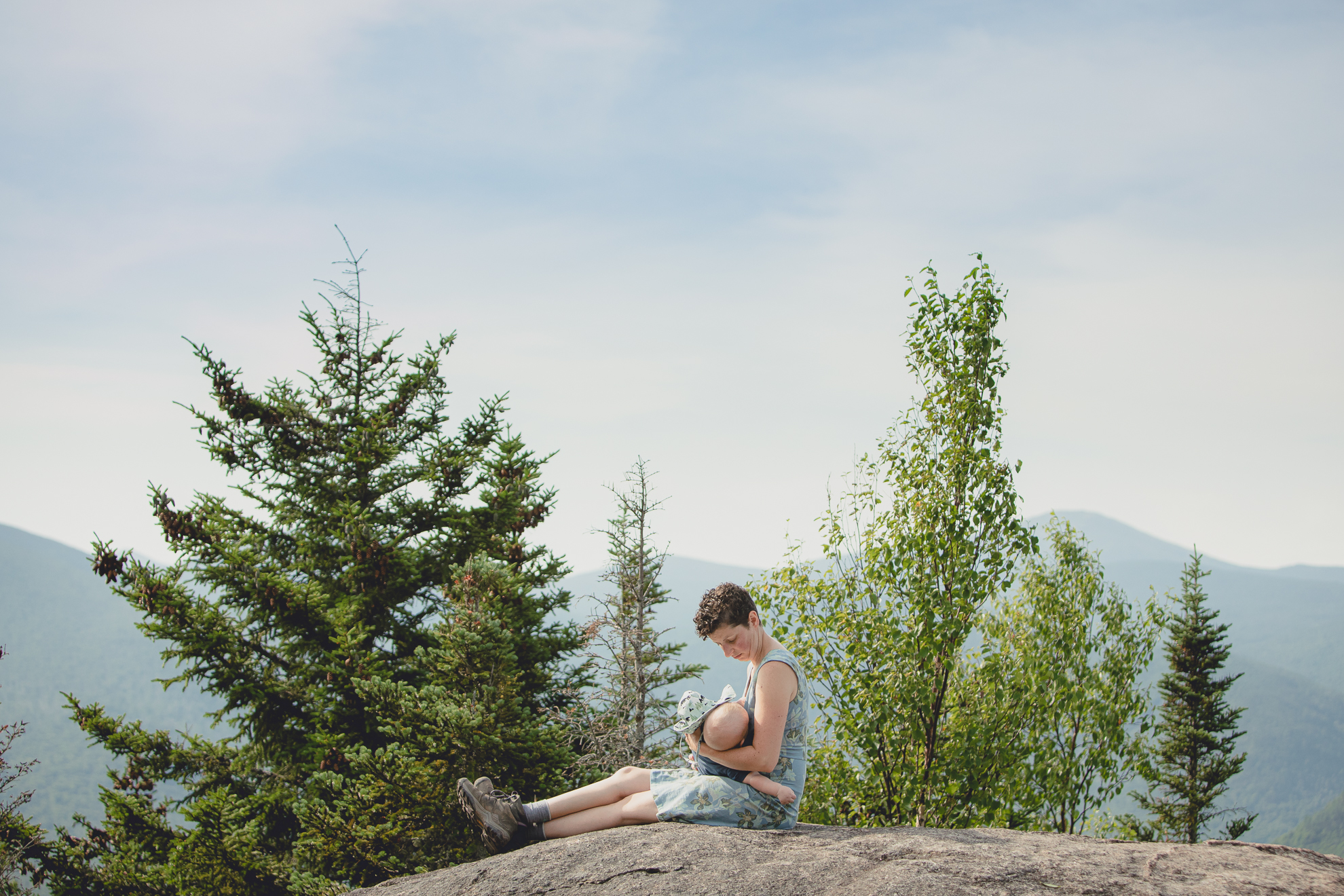 mom breastfeeds baby on top of Mount Jo during their photojournalistic family photography session in the Adirondack High Peaks Region of NY