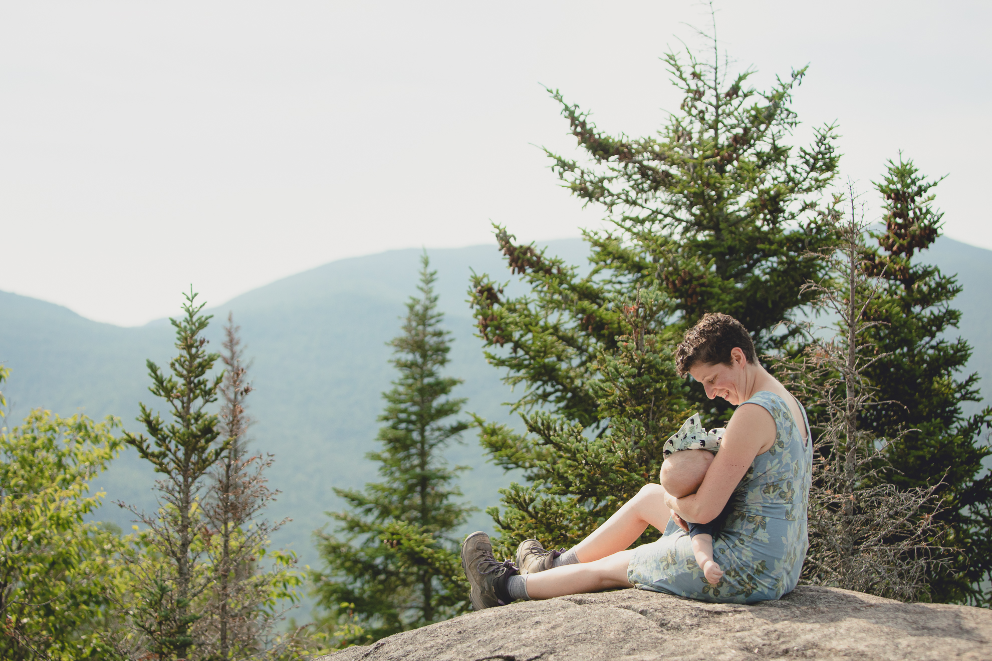 mom breastfeeds baby on top of Mount Jo during their photojournalistic family photography session in the Adirondack High Peaks Region of NY