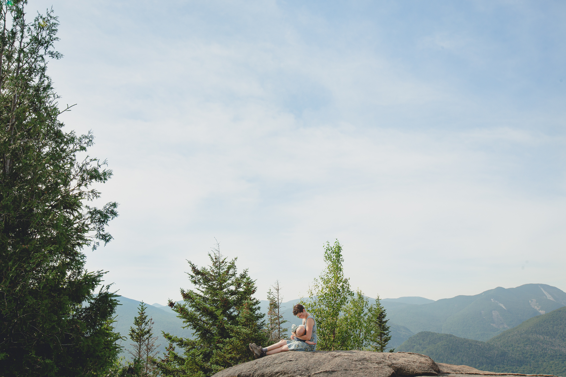 mom breastfeeds baby on top of Mount Jo during their photojournalistic family photography session in the Adirondack High Peaks Region of NY