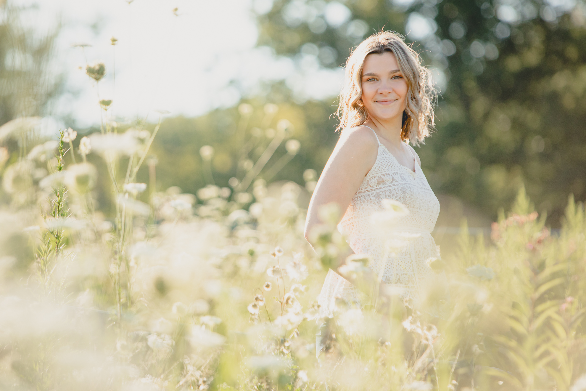 maple grove student smiles in queen anne's lace field during senior portrait photography session at Chautauqua Institution