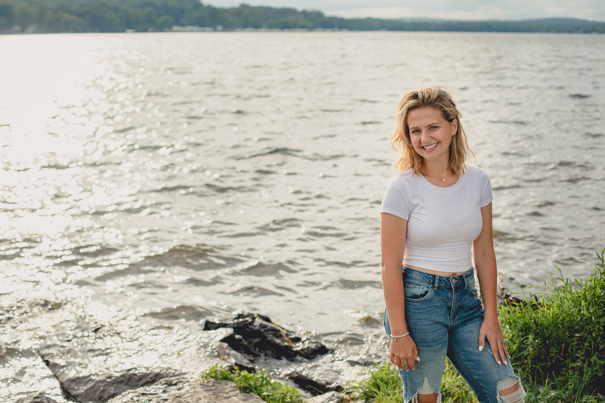 WNY senior smiles for photographer during portrait session at Long Point State Park on Lake Chautauqua in Bemus Point, NY