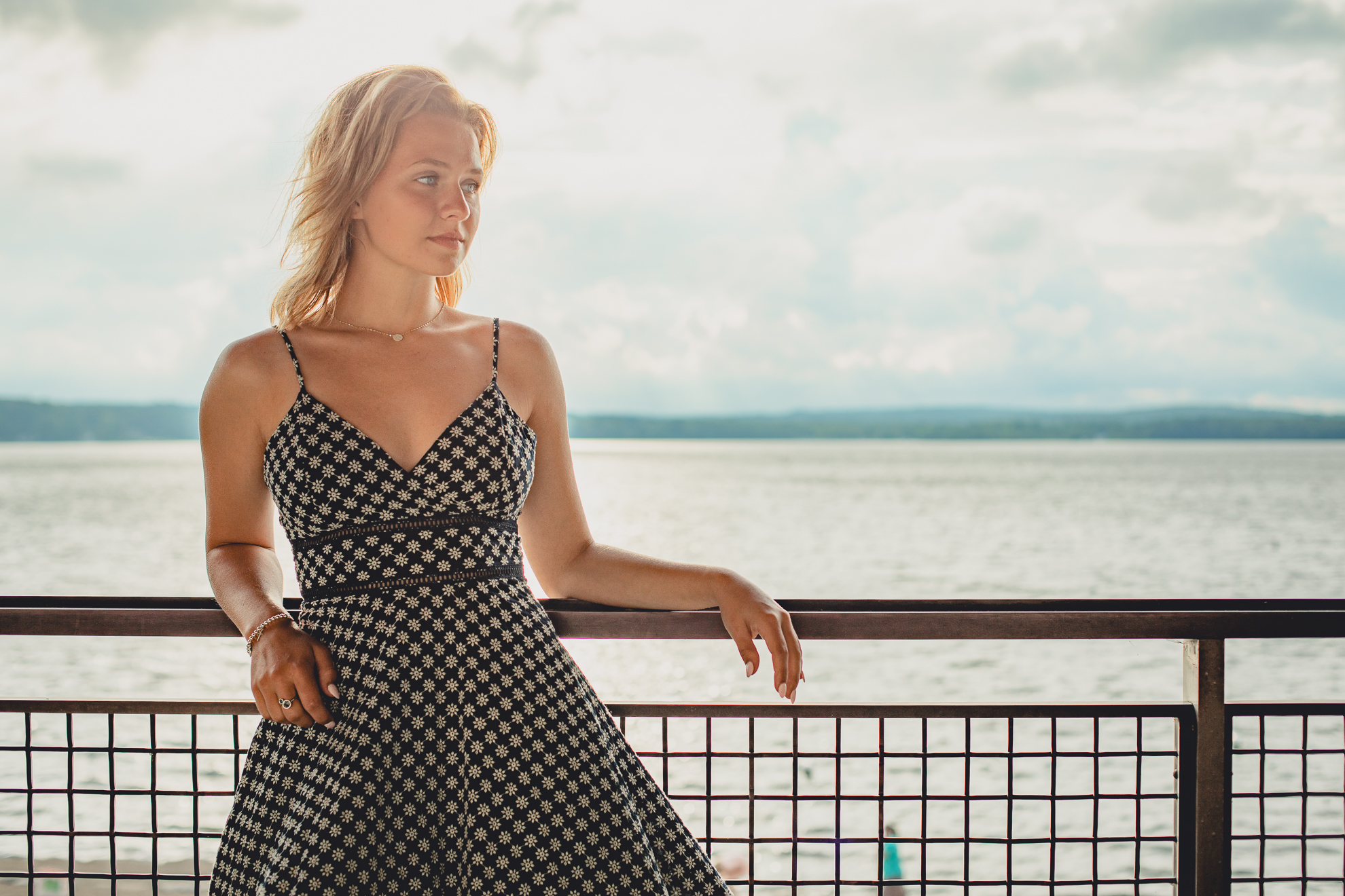 wny student stands on balcony of bath house during senior portrait photography session at Long Point State Park on Lake Chautauqua in Bemus Point, NY
