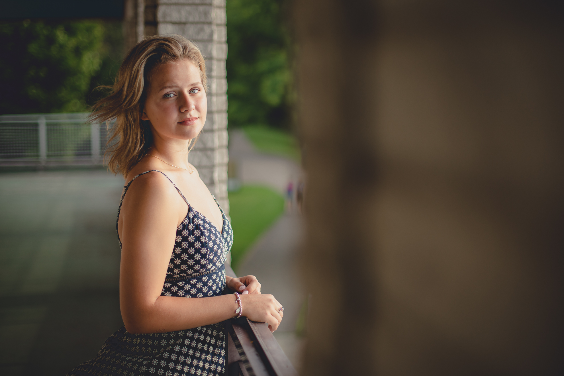 wny student stands on balcony of bath house during senior portrait photography session at Long Point State Park on Lake Chautauqua in Bemus Point, NY