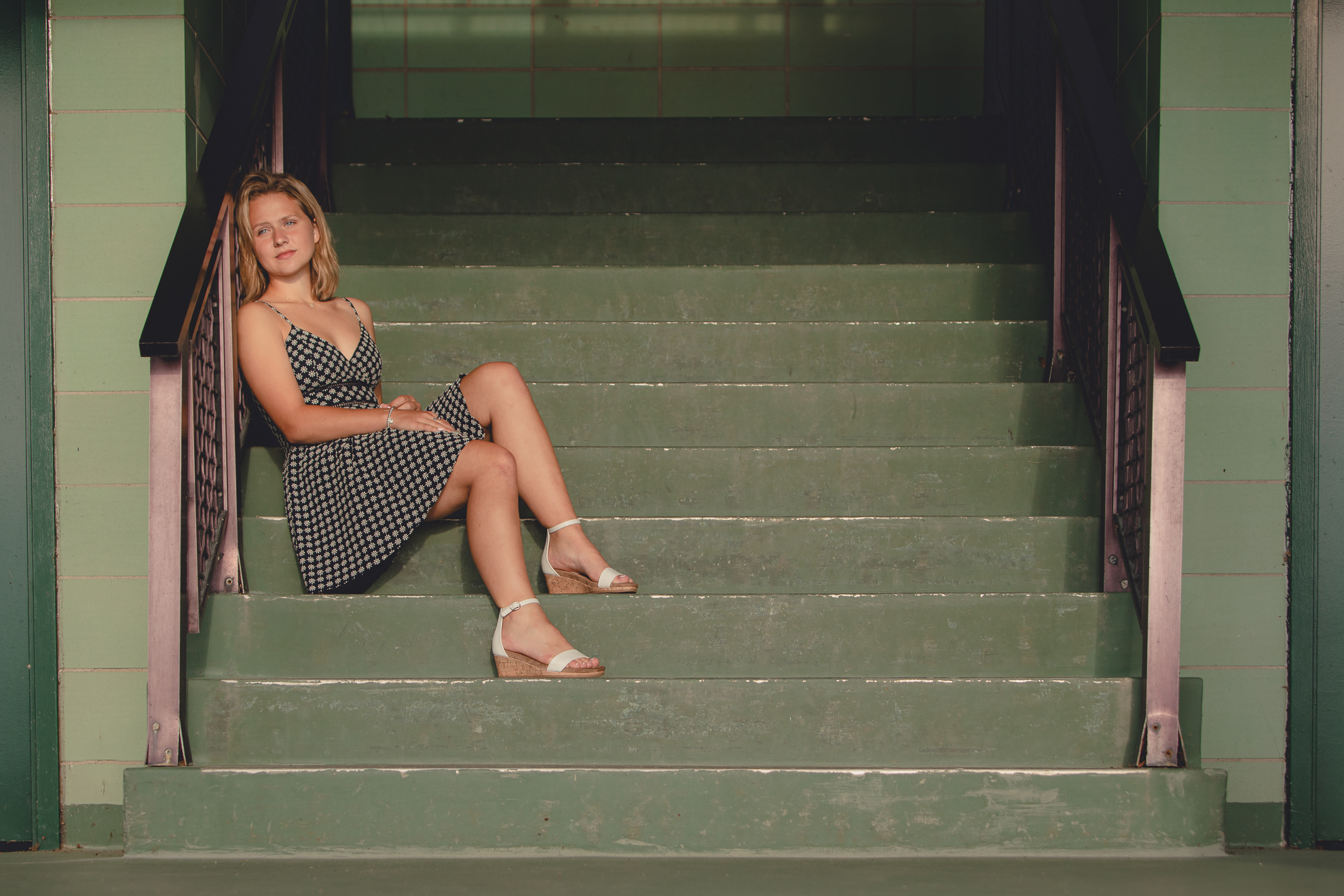 wny student sits on steps of bath house during senior portrait photography session at Long Point State Park on Lake Chautauqua in Bemus Point, NY