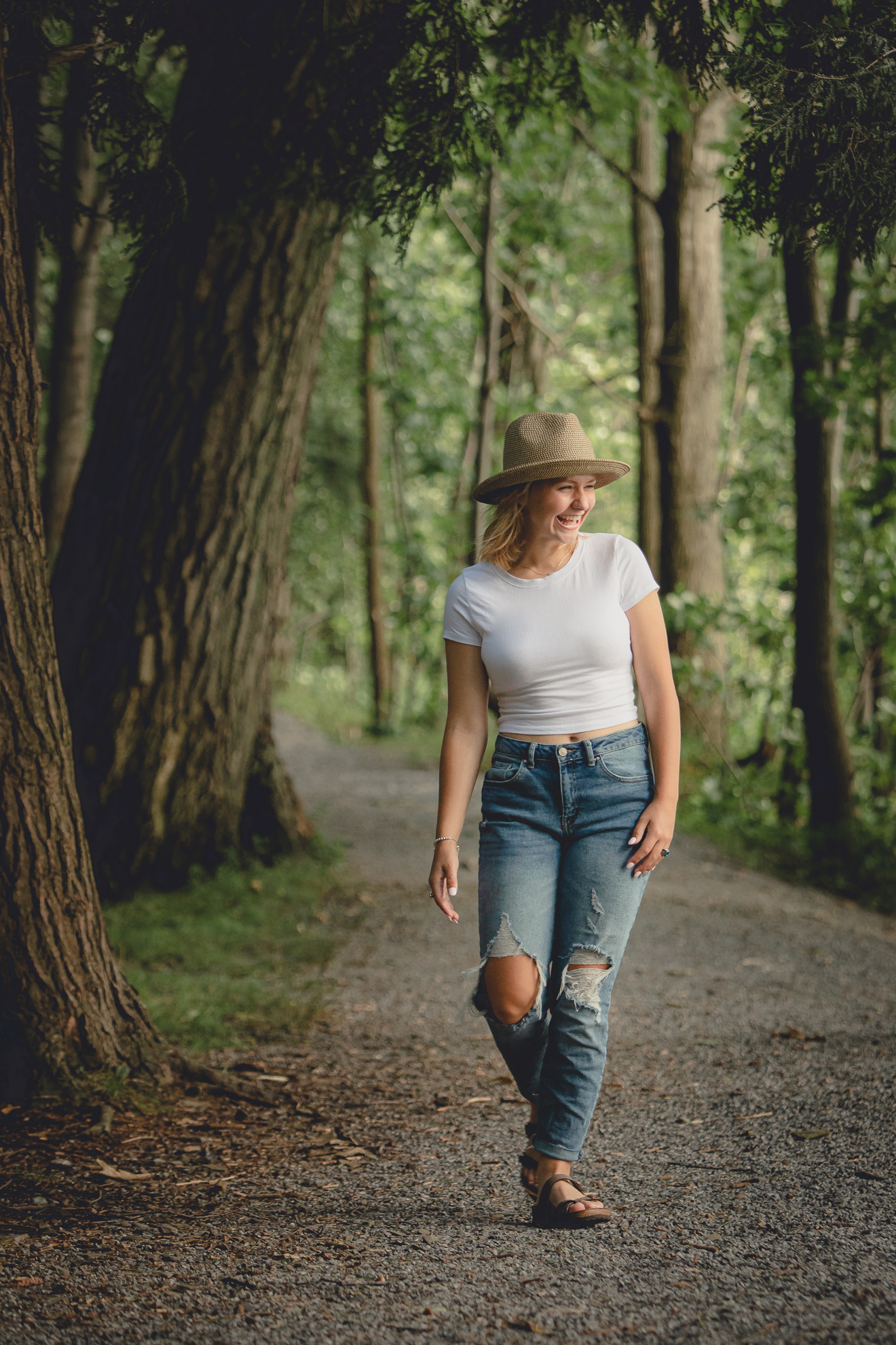 wny student walks on path laughing during senior portrait photography session at Long Point State Park on Lake Chautauqua in Bemus Point, NY