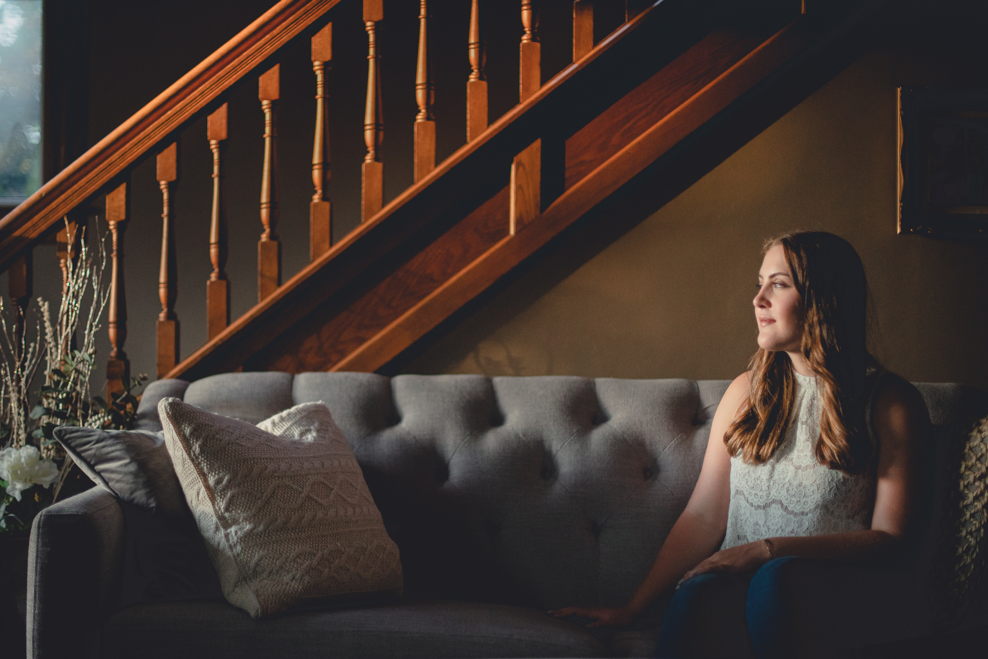 Tessa in sunset golden hour light in on couch in living room during senior portrait photography session near Buffalo, NY