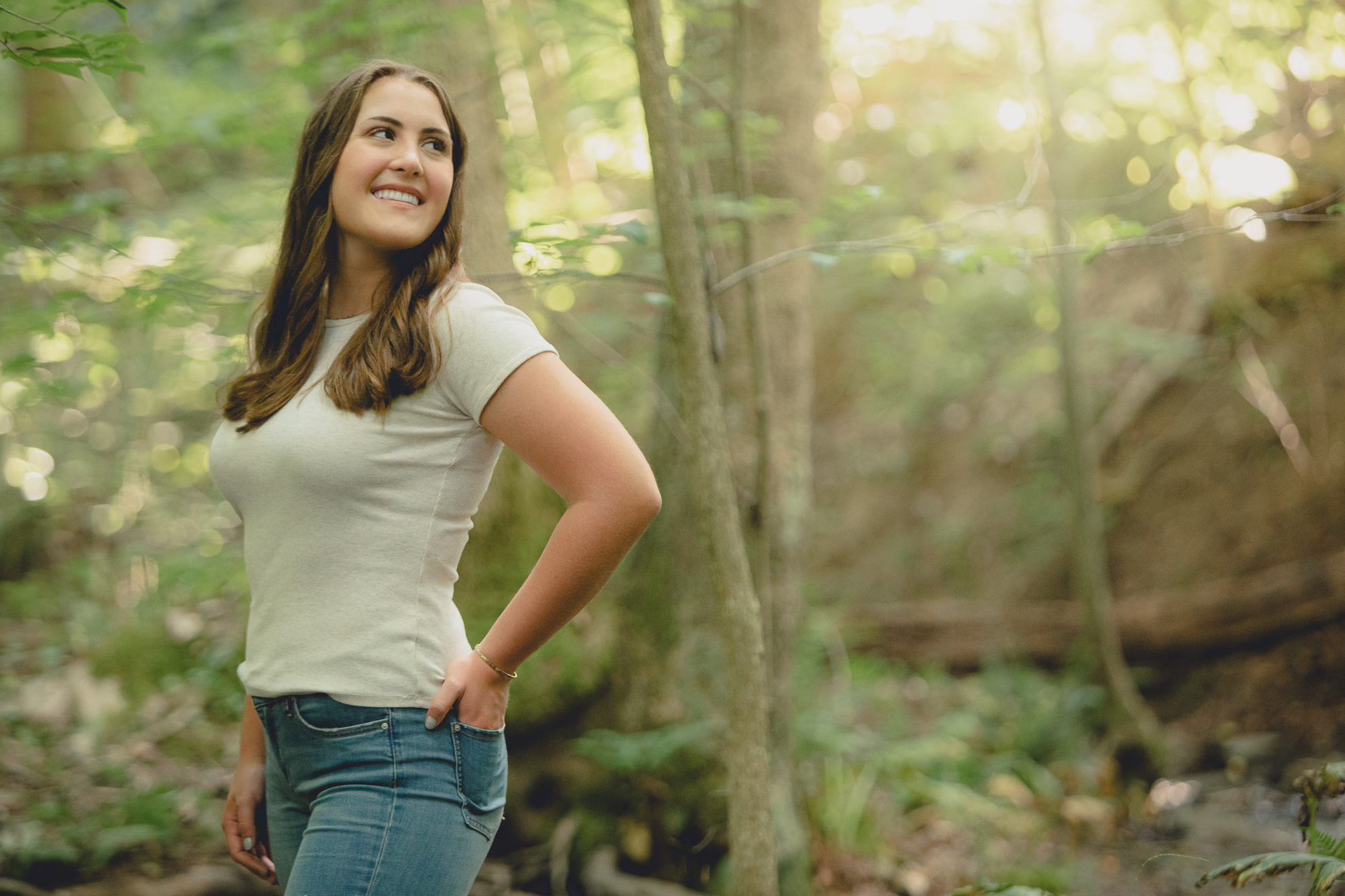 Tessa smiles over shoulder in woods during senior portrait photography session in Long Point State Park in WNY