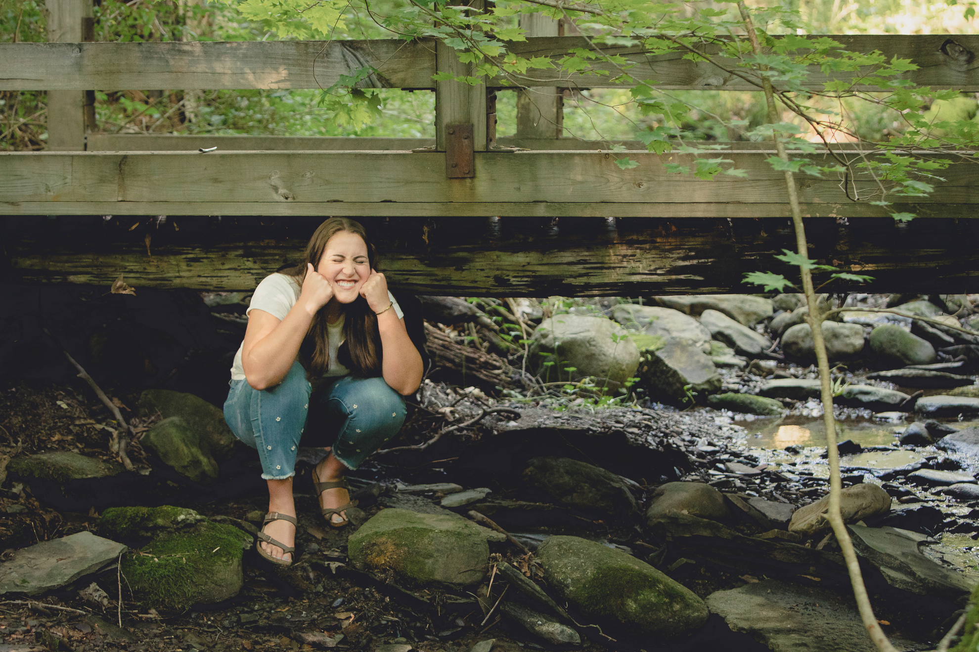 Tessa pretends to be a troll under bridge during senior portrait photography session in Long Point State Park in WNY