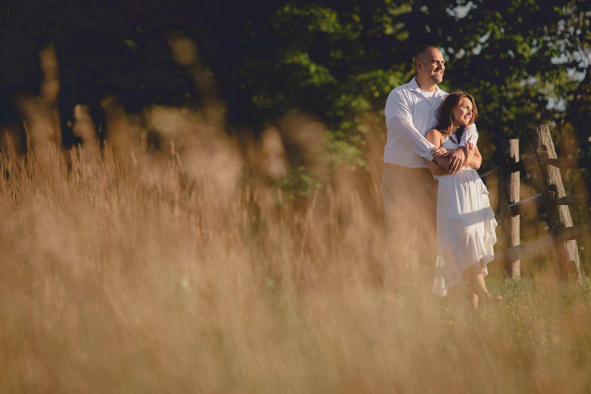 groom wraps arms around bride in field during wedding photography engagement portrait session at Knox Farm near Buffalo, NY