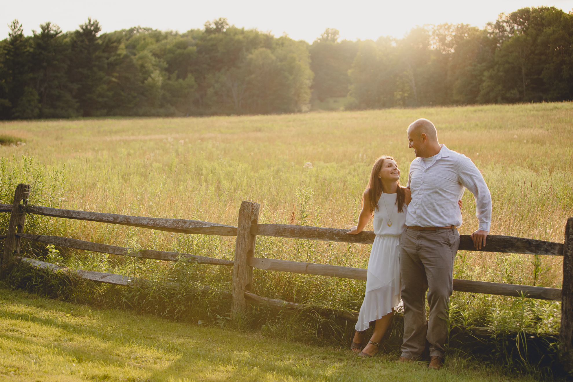 bride and groom stand against fence in field during wedding photography engagement portrait session at Knox Farm near Buffalo, NY