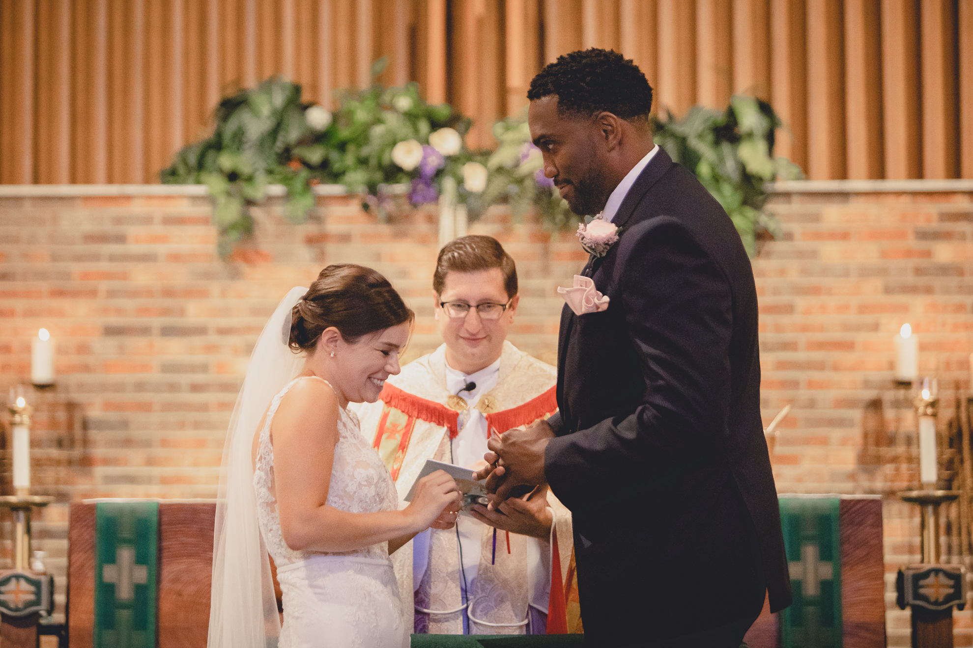 bride and groom exchange rings during micro wedding ceremony at St. Peter's Church in Lewiston, NY