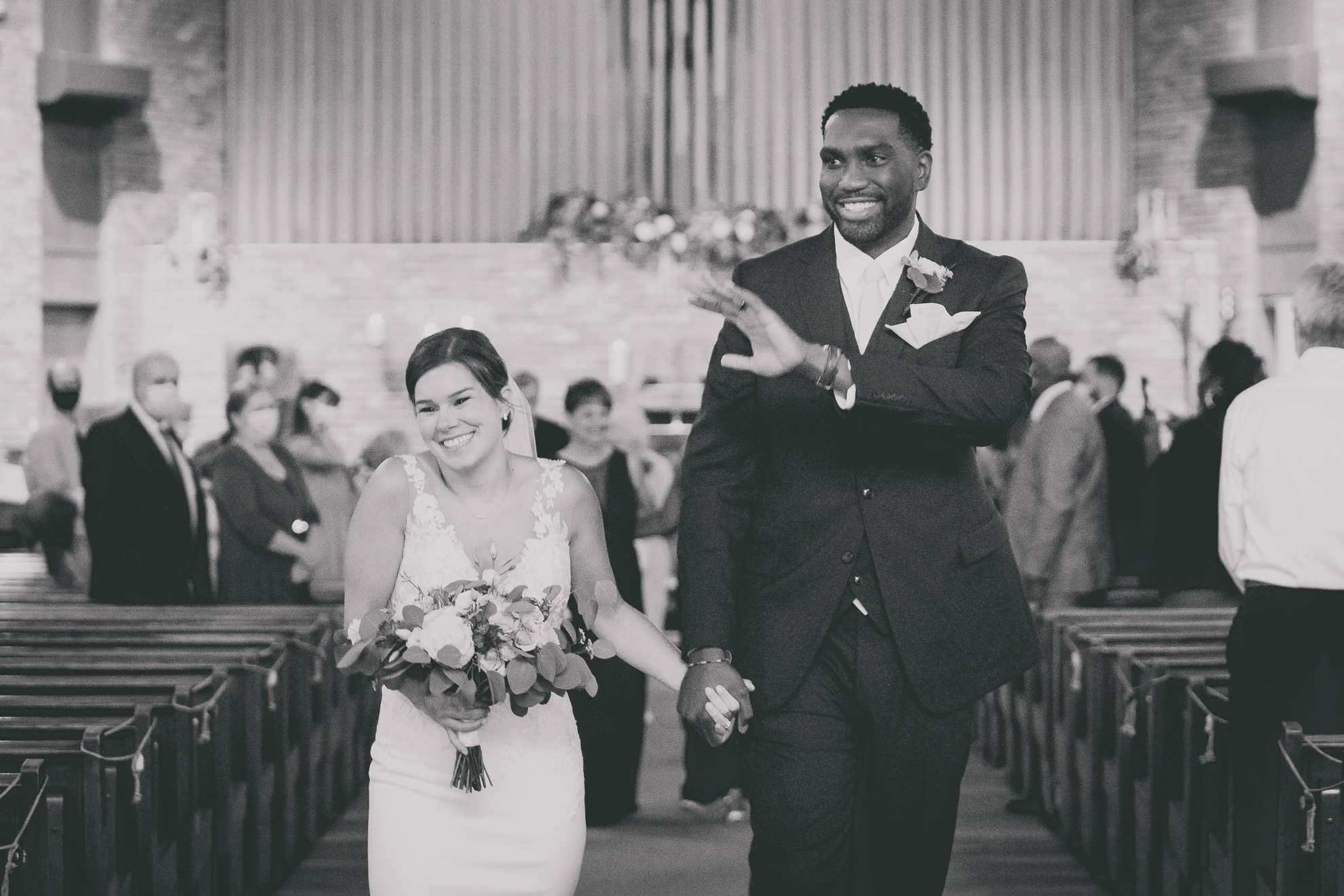 bride and groom wave to guests during micro wedding ceremony at St. Peter's Church in Lewiston, NY