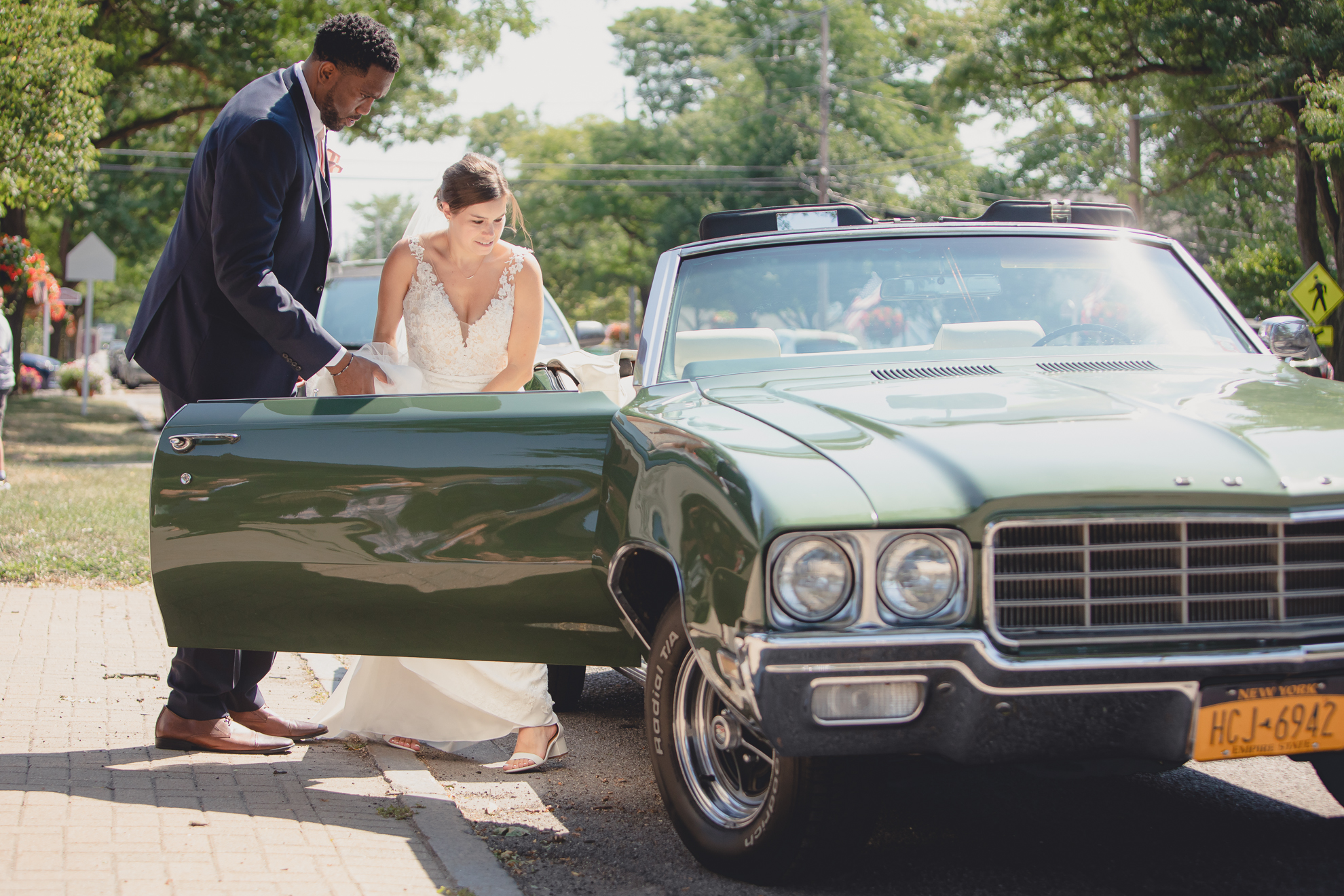 groom opens door of vintage Buick for bride after micro wedding ceremony at St. Peter's Church in Lewiston, NY