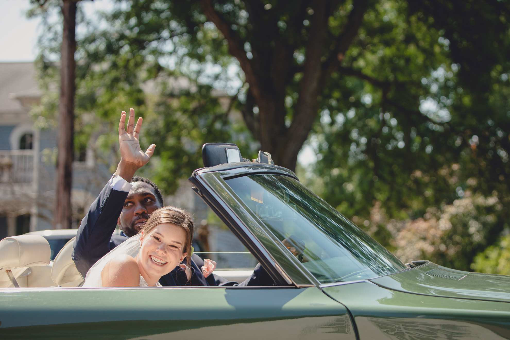 groom waves to guests from vintage buick after micro wedding ceremony at St. Peter's Church in Lewiston, NY